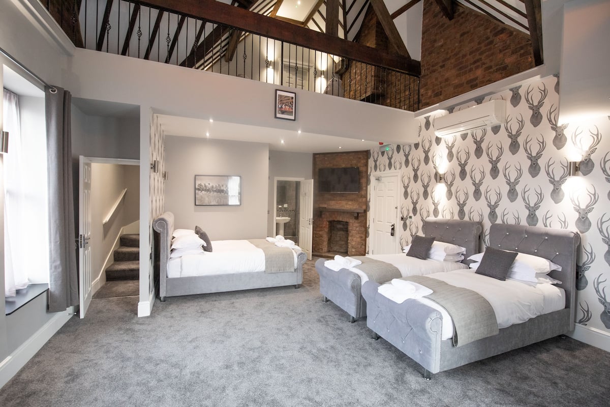 A bedroom with two beds, a fireplace, and a staircase leading to an upper level.
