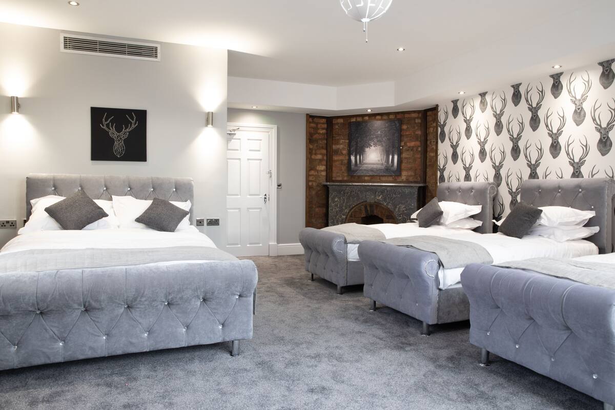 A bedroom with two large beds, a fireplace, and a wall with deer head decorations.