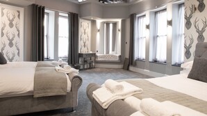 A hotel room with two beds, a seating area, and large windows.