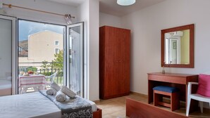 A bedroom with a bed, a wooden wardrobe, a desk with a chair, and a large mirror. - Socrates Studios (Kefalonia)