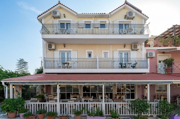 Un bâtiment à deux étages doté d’un balcon et d’un espace extérieur aménagé pour s’asseoir.