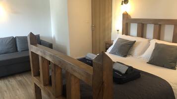 A room with a bed, a wooden headboard, a nightstand, a lamp, and a sofa.