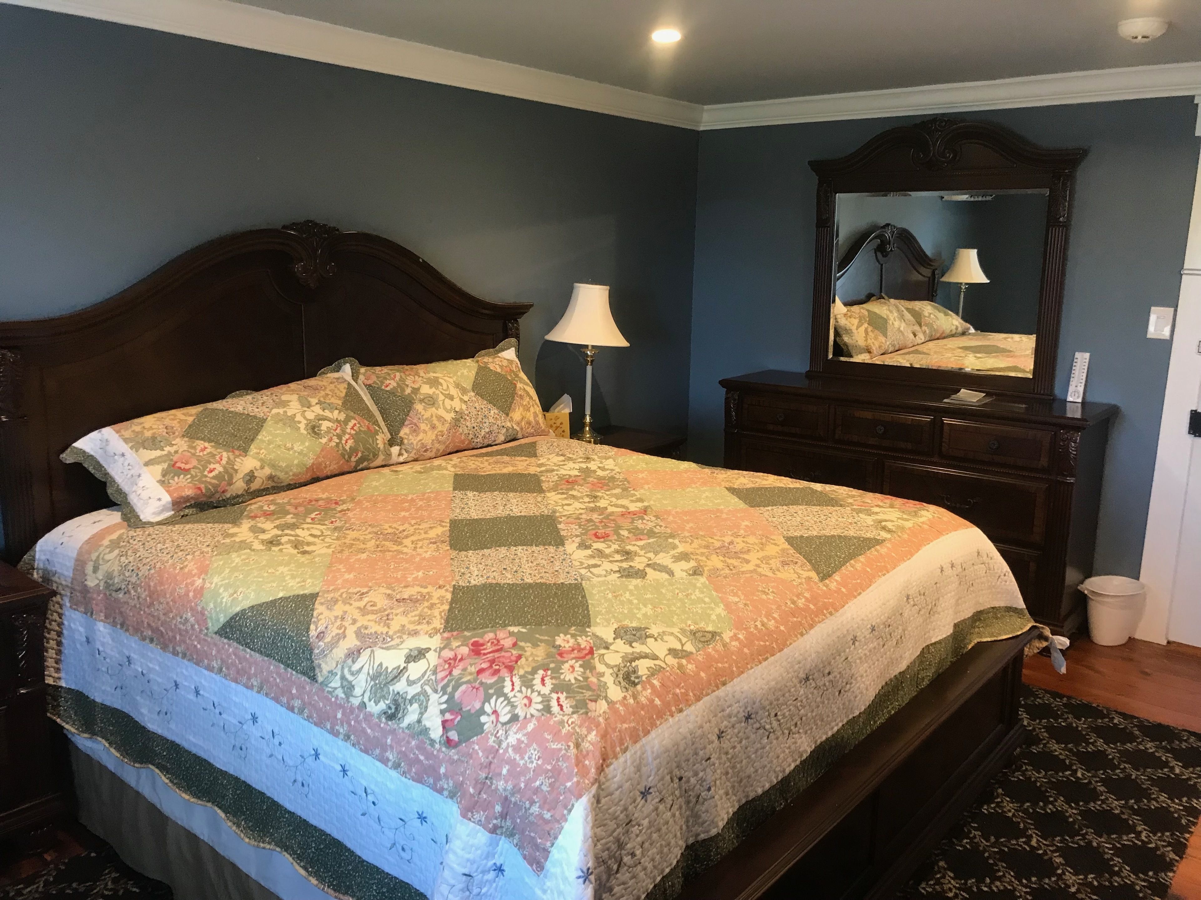 Une chambre à coucher avec un grand lit, une commode, un miroir et une table de chevet.