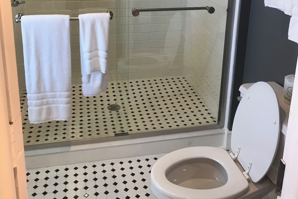 A bathroom with a glass-enclosed shower, a toilet, and a tiled floor.