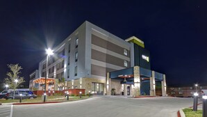 A modern hotel with a flat roof, multiple entry points, and a well-lit exterior.