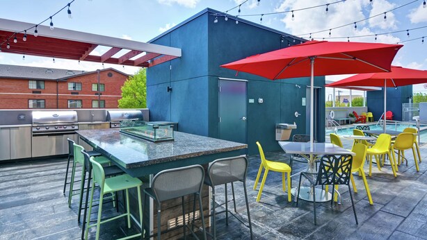 An outdoor patio with a bar area, seating, and a pool.