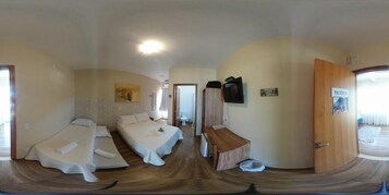 Una habitación con dos camas, un armario de madera, un televisor y una puerta con la etiqueta "PACIENTIA".