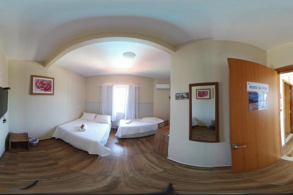 A room with two beds, a TV, a painting, and a door labeled "PONTA DA UIGIA".