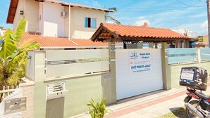 A gated entrance with a sign for a business, a motorcycle parked nearby, and a building with a tiled roof. - Pousada Mar de Almirante (Penha)