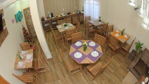 Un comedor con varias mesas y sillas de madera, una cocina al fondo y un árbol de Navidad.