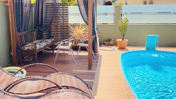A rooftop pool area with a wooden deck, a covered seating area, and a pool. - Pousada Mar de Almirante (Penha)