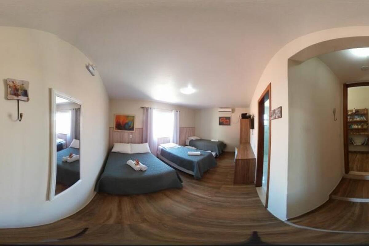 A room with two beds, a mirror, and a wooden floor.