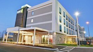 A modern hotel with a covered entrance, multiple floors, and a well-lit facade.