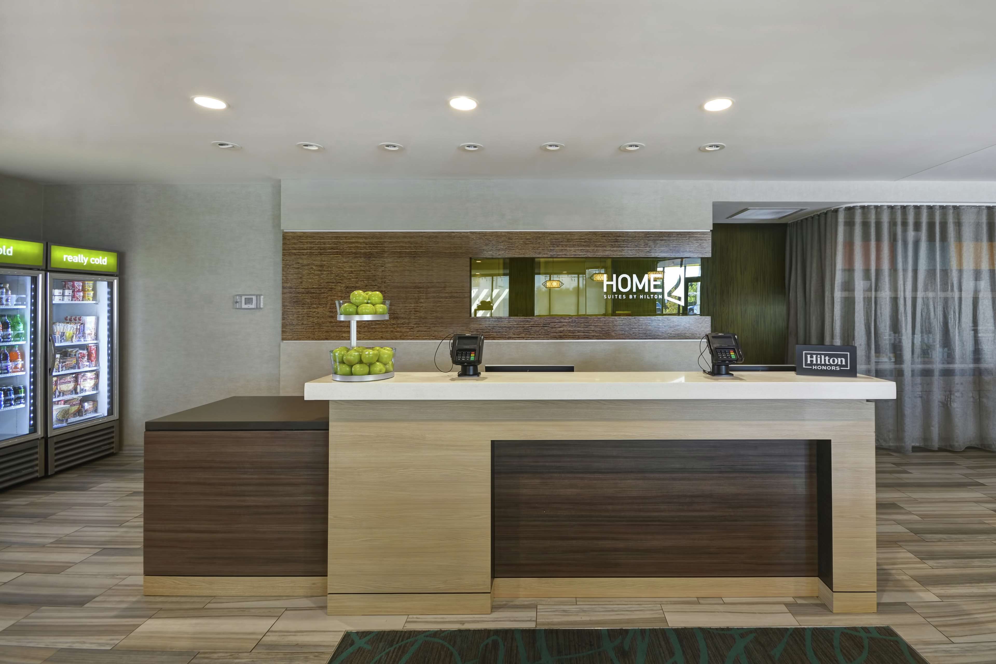 A hotel reception area with a modern design, including a counter, a fruit display, and a sign for 'Hilton Honors'.