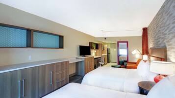 Une chambre d’hôtel avec un lit, un bureau, une télévision et une salle de bain visible à travers une porte ouverte.