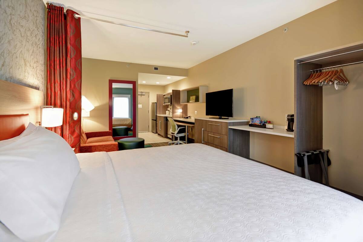 Habitación de hotel con una cama grande, un escritorio con computadora, un televisor y un armario.