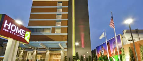 Ett hotell med modern design, som kännetecknas av en tydlig skylt med ordet ”HOME” och en stor, upplyst, vertikal skylt.