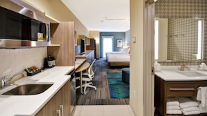 Hotelkamer met kitchenette, een bed, een badkamer en uitzicht op de gang.