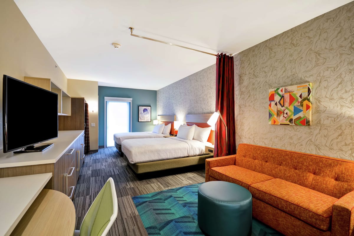 Una habitación de hotel con cama, televisión, escritorio, silla y sofá.