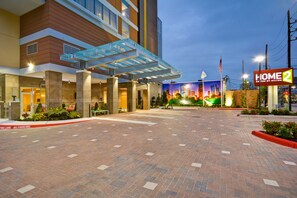 L'ingresso di un hotel con una tettoia, un cartello che indica divieto di sosta e la segnaletica 'Home 2 Suites by Hilton'.