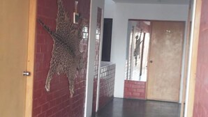 Een gang met een muurschildering van een giraffe aan de linkerwand, een houten deur en een betonnen vloer.