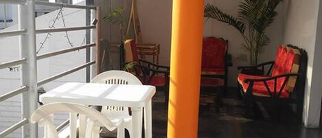 A room with a black floor, white plastic chairs, a red chair, and a large orange pillar.