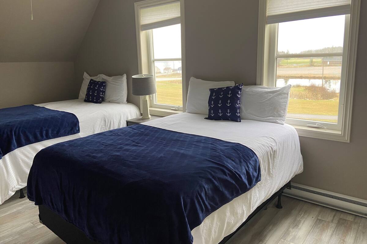 Ein Schlafzimmer mit zwei Betten, einem Deckenventilator und Fenstern mit Jalousien.