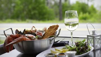 A meal with seafood, breaded items, and a glass of white wine on a table with a scenic view.
