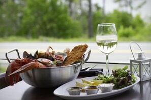 Un repas composé de fruits de mer, d’aliments panés et accompagné d’un verre de vin blanc, le tout servi sur une table offrant une vue panoramique.