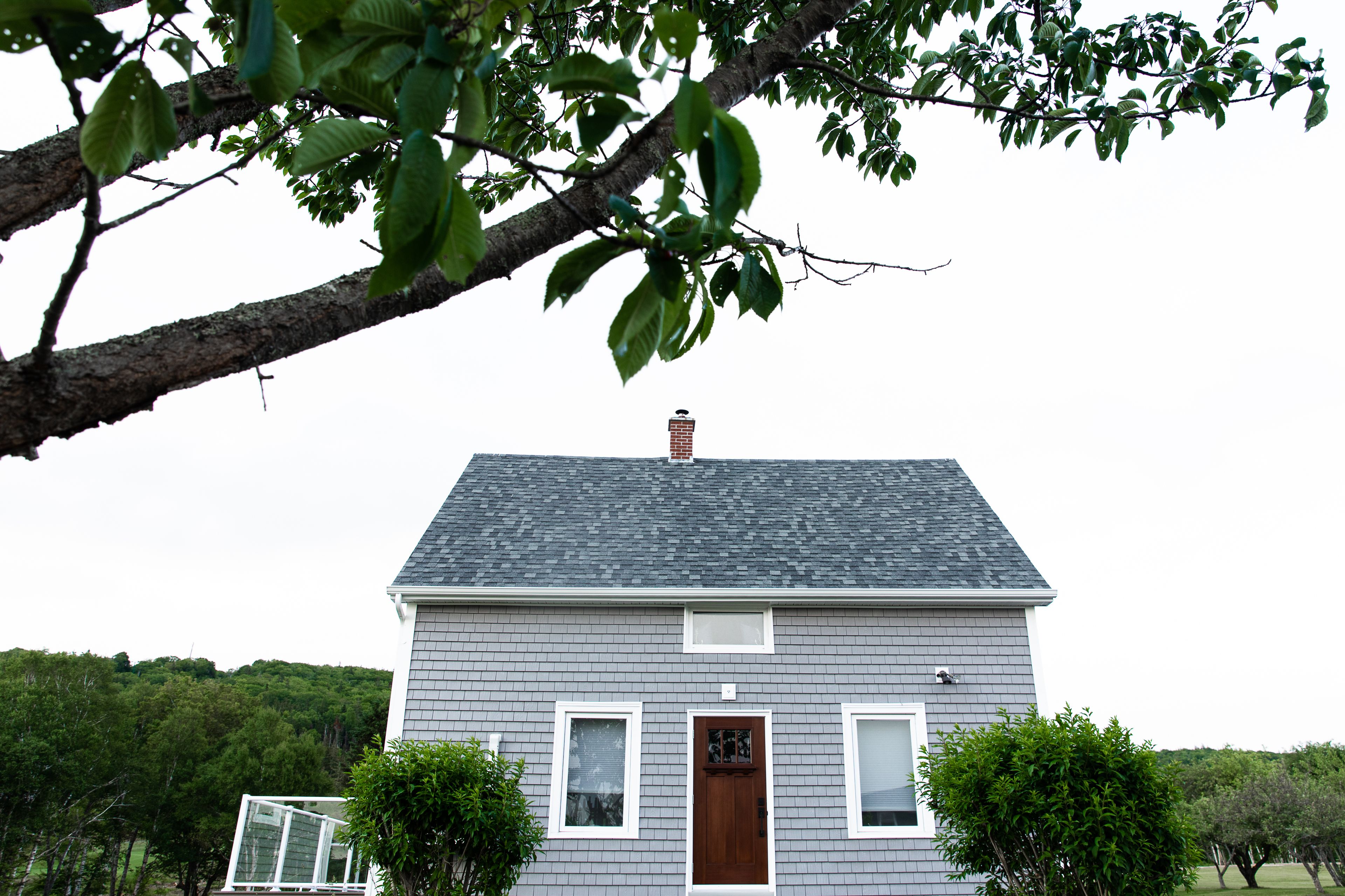 A house with a grey roof, white trim, and a brown door.