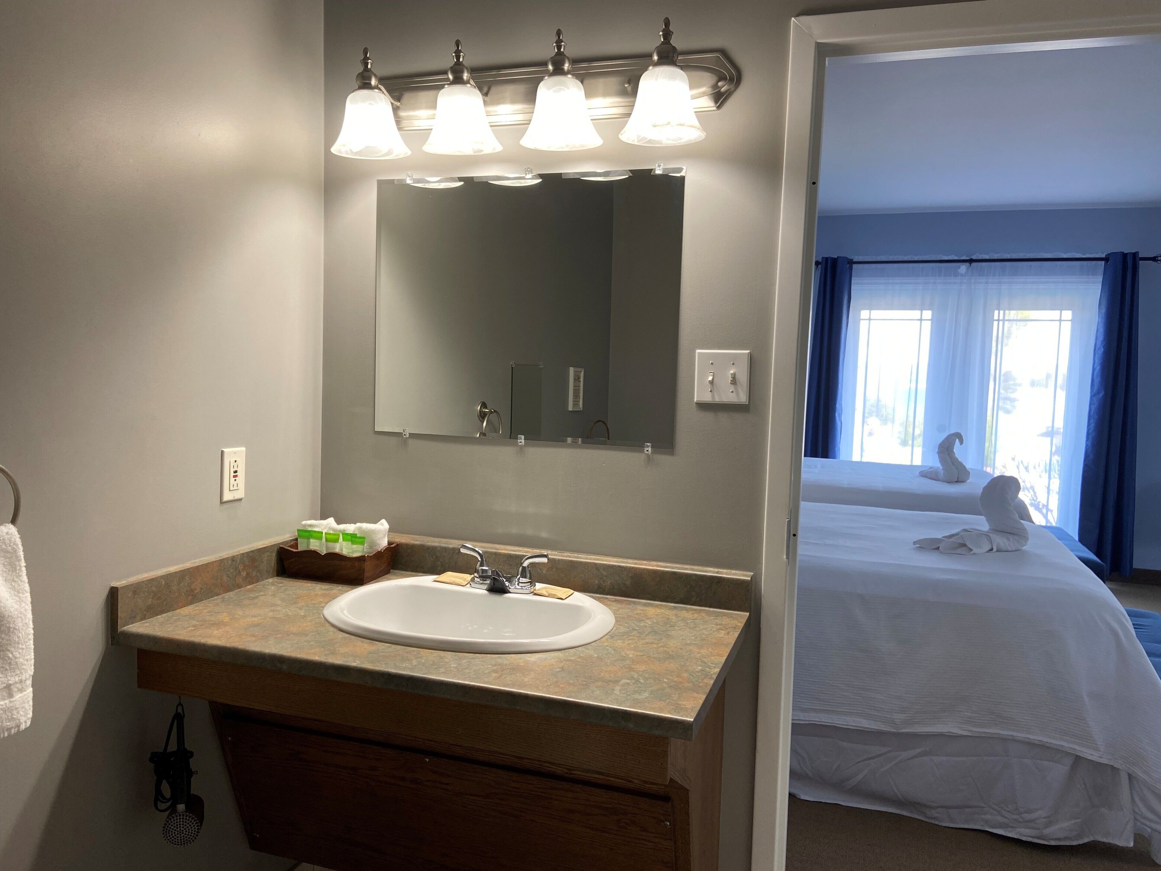 A bathroom with a sink, mirror, and three light fixtures above it.