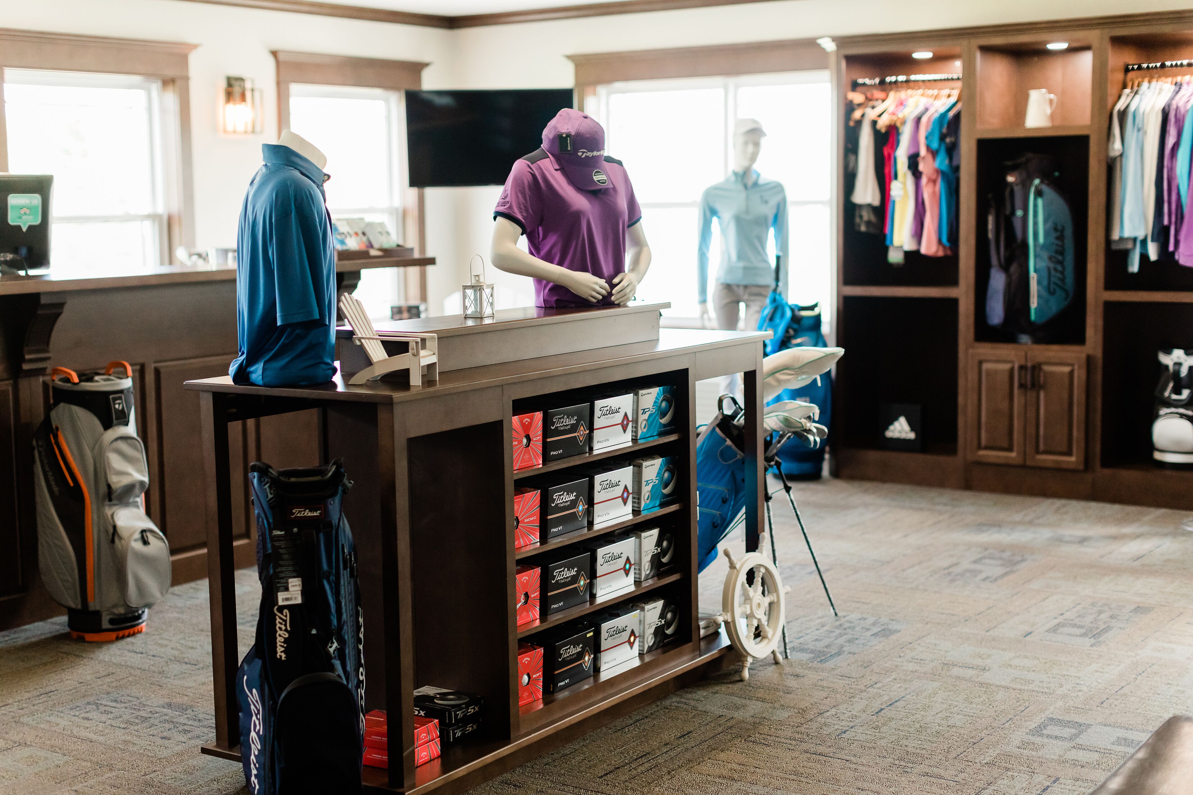 Una tienda de golf con exhibición de bolsas y ropa deportiva.