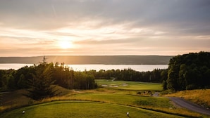 Een golfbaan met een meer op de achtergrond, omringd door bomen.
