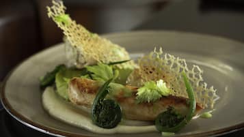 A plate of food with a piece of fish, greens, and a decorative element.