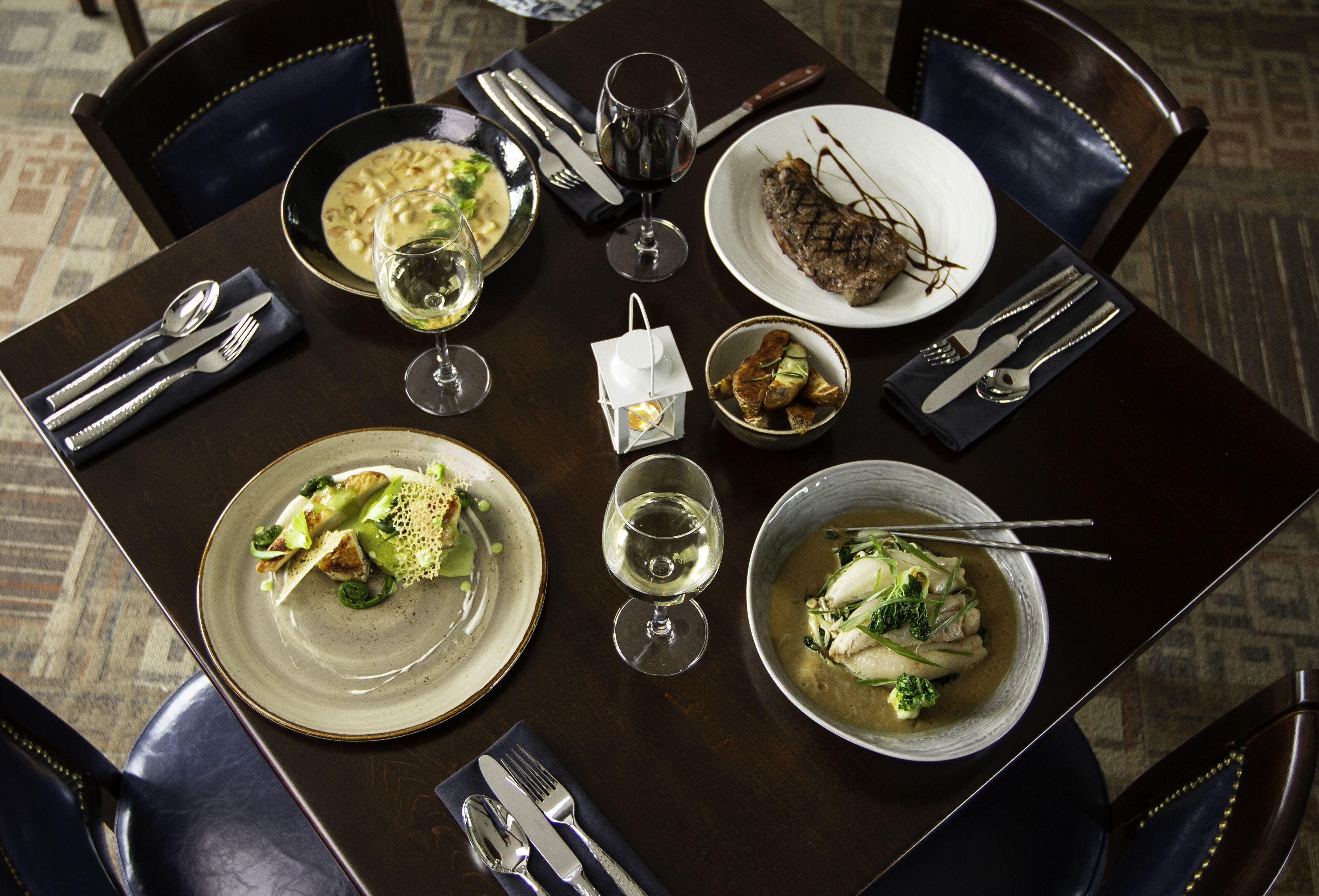 A dining table set with plates, bowls, cutlery, and glasses, suggesting a meal setting.