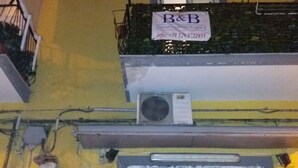 A building with a yellow facade, a B&B sign, an air conditioning unit, and a door with a number '66' on it. - B&B Appartamenti Napoli (Naples)