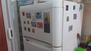 A white refrigerator with various magnets and stickers, a wooden spoon in a jar, and a blue checkered tablecloth. - B&B Appartamenti Napoli (Naples)