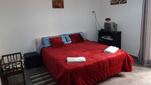 A bedroom with a red bedspread, a small TV on a stand, and a painting on the wall. - B&B Appartamenti Napoli (Naples)