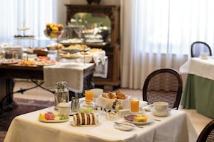 A breakfast buffet with various food items and beverages on a table, set in a room with a view of the outdoors.