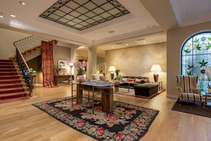 A spacious living area with a staircase, a dining table, and a large window with a stained glass design.