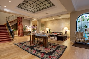 A spacious living area with a staircase, a dining table, and a large window with a stained glass design.