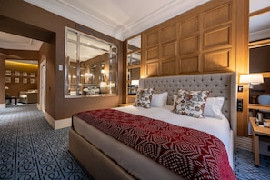 A hotel room with a large bed, a wooden headboard, a mirror, and a view of the bathroom.