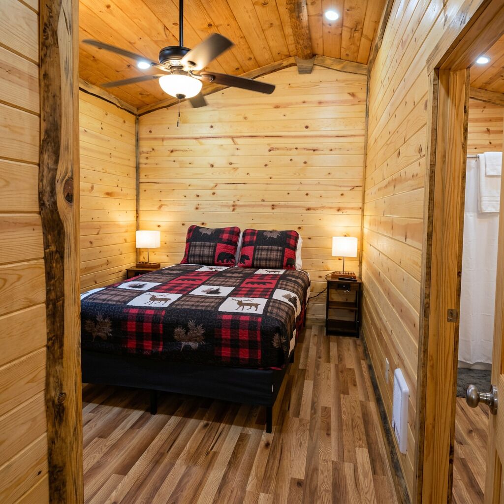 Une chambre à coucher dans une cabane en bois, avec un lit, deux lampes de chevet, un ventilateur de plafond et un radiateur.