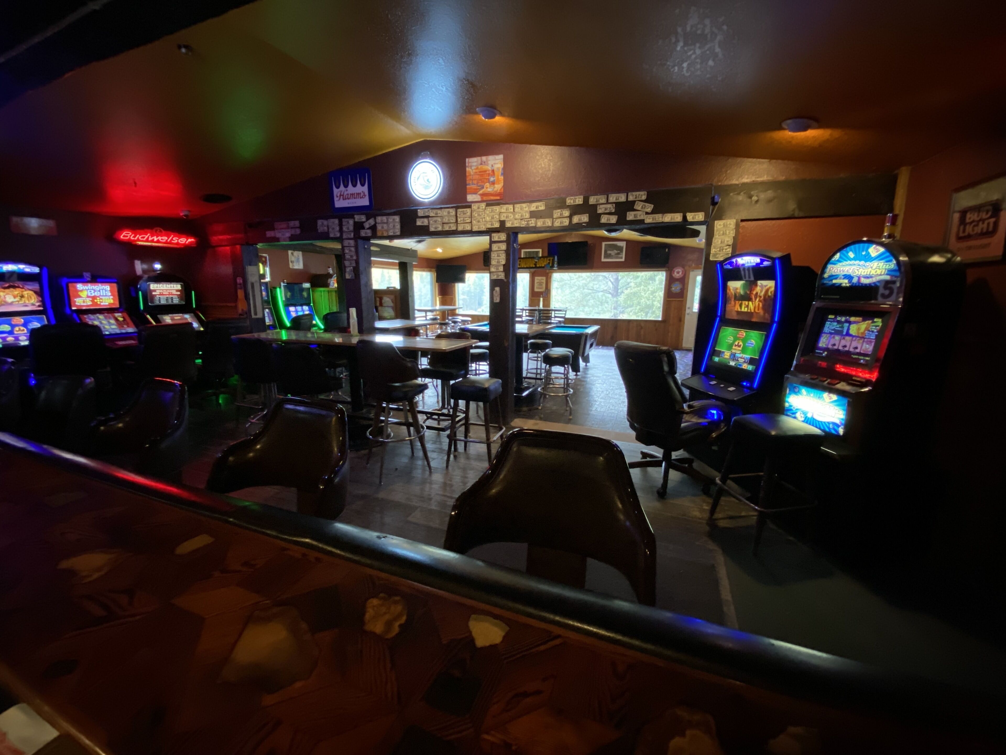Zona bar con diverse slot machine, sgabelli da bar e tavolo da biliardo.