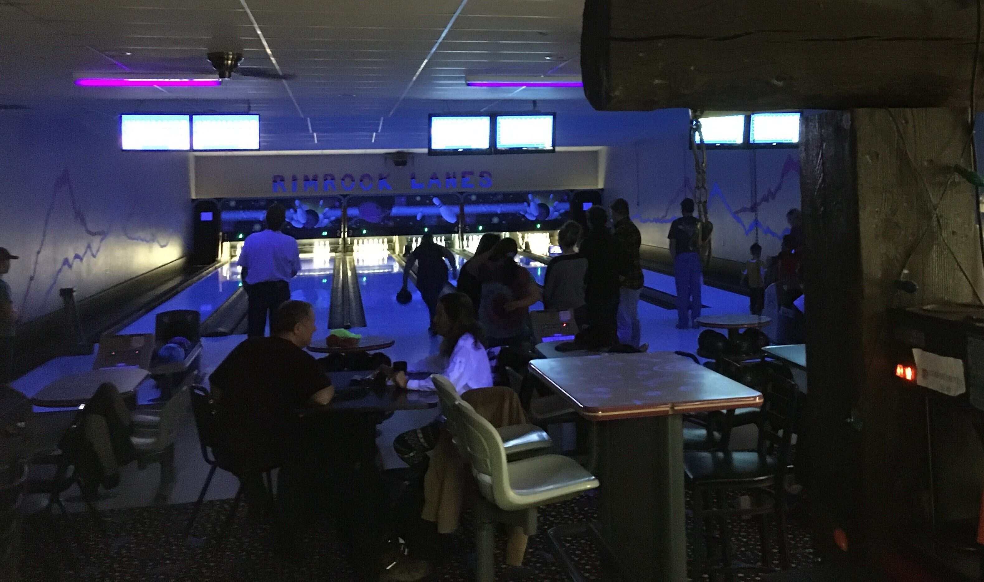 Un bowling doté de nombreuses pistes, de tables et de chaises pour les spectateurs.
