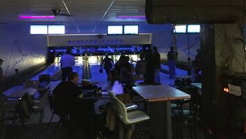 Un bowling doté de nombreuses pistes, de tables et de chaises pour les spectateurs.
