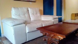 Ein weißes Ledersofa vor einer gelben Wand mit blauem Akzent.