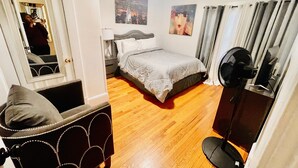 A bedroom with a bed, a chair, a standing fan, and a mirror. - Cozy & Spacious Entire Home in Springfield (Springfield)