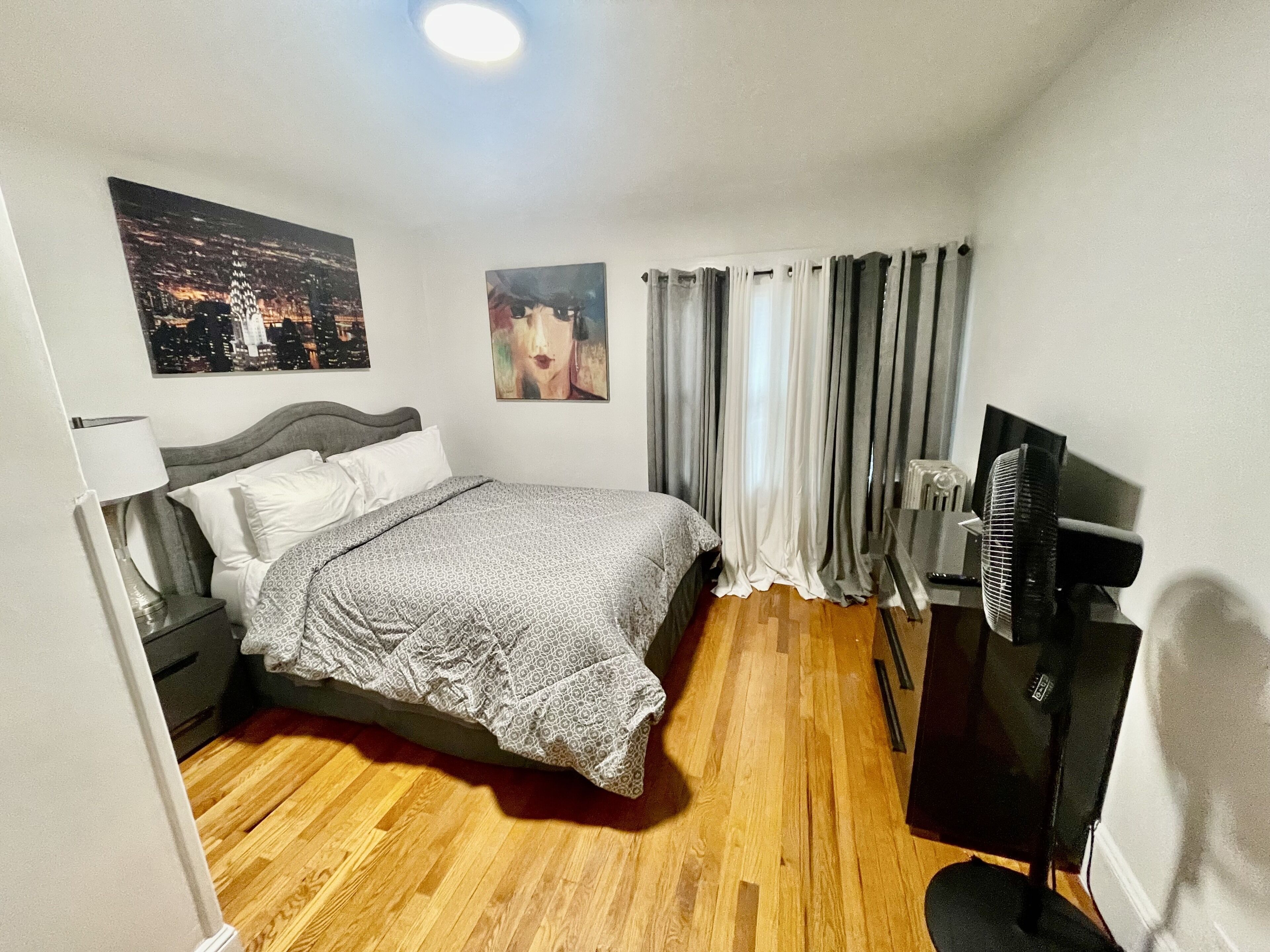 Une chambre d’hôtel avec un lit, un bureau, une chaise, une télévision et des rideaux.