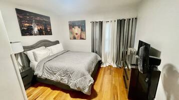 Une chambre d’hôtel avec un lit, un bureau, une chaise, une télévision et des rideaux.